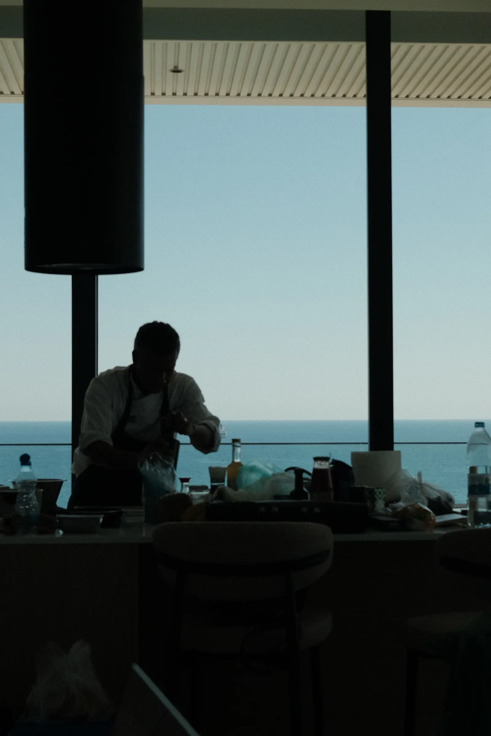 Dominique Benihoud cooking in a kitchen in front of a window onto the sea