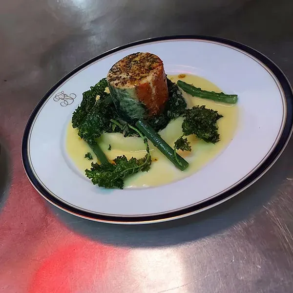 A stuffed fillet on crisp kale and green beans in a yellow butter sauce